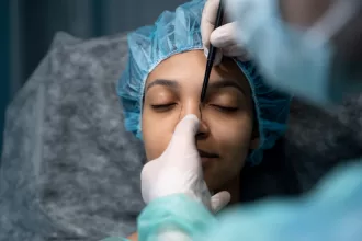 A woman receiving Botox and fillers treatment on her nose from a professional doctor in a clinical setting.