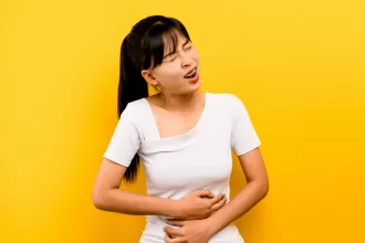 Woman experiencing stomach pain, set against a yellow background, symbolizing the impact of Congenital Diaphragmatic Hernia Repair.