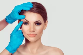 A woman receiving eyebrow shaping in a beauty salon, highlighting the art of eyelid surgery and brow enhancement.