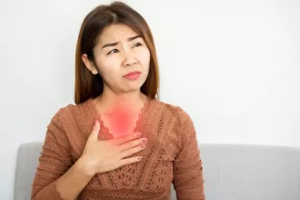 Woman experiencing chest pain, holding her heart, symbolizing the impact of GERD surgery on her health.