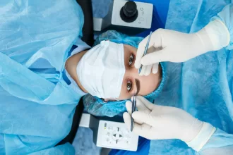 A woman in a blue gown sits in a dental chair as a hygienist cleans her teeth, showcasing a routine dental check-up.