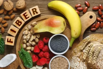 A colorful assortment of high-fiber, low-FODMAP foods, including fresh vegetables like zucchini, carrots, and spinach, alongside fruits such as oranges and bananas, and a bowl of quinoa and oats.