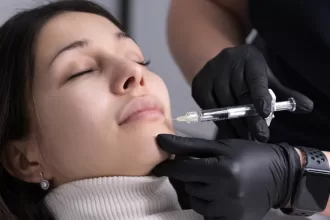 A woman receiving a facial treatment, specifically lip augmentation, from a professional doctor in a clinical setting.