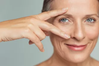 A woman with blue eyes and a bright smile, showcasing her recovery after orbital fracture repair surgery.
