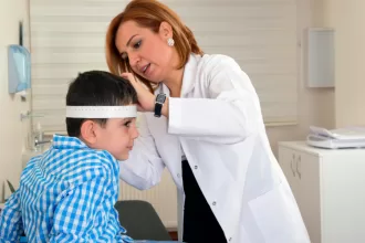 A woman examines a young boy's head, focusing on pediatric neurosurgery concerns like hydrocephalus and tumors.