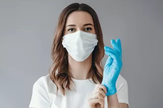 A woman in a surgical mask and blue gloves, emphasizing the importance of sterilization in healthcare settings.