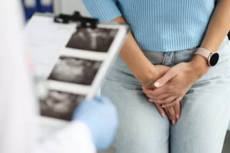 A woman places her hand on a doctor's clipboard, discussing details about her ovarian cystectomy procedure.