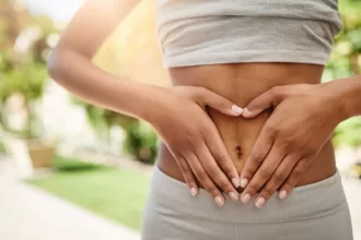 A woman gently rests her hands on her stomach, symbolizing recovery after an abdominoplasty procedure.