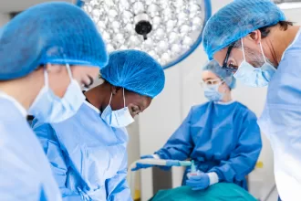 A surgeon performing minimally invasive cardiac surgery with advanced robotic tools in a sterile operating room.